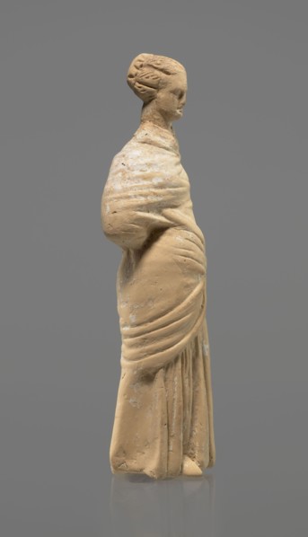Terracotta figurine of a standing woman. Terracotta, molded figurine, Tanagra figurine. Figurine of