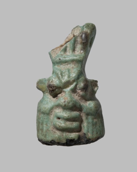 Amulet in the shape of Bes's head decorated with a crown. The grotesque face with sideburns is