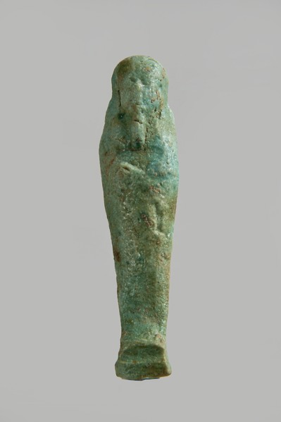 Ushabti figurine, very schematically designed. Distinct narrow beard, tools in crossed hands. Flat