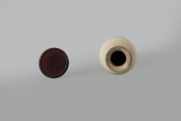 Cylindrical porcelain vase tapering toward the bottom with a flat rim; light cream glaze with fine