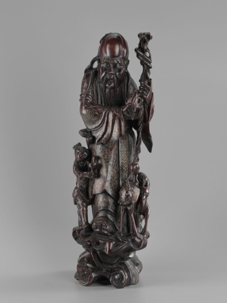 Deity of Longevity Shouxing/Shoulao holds a long traveling staff and a peach of immortality; his