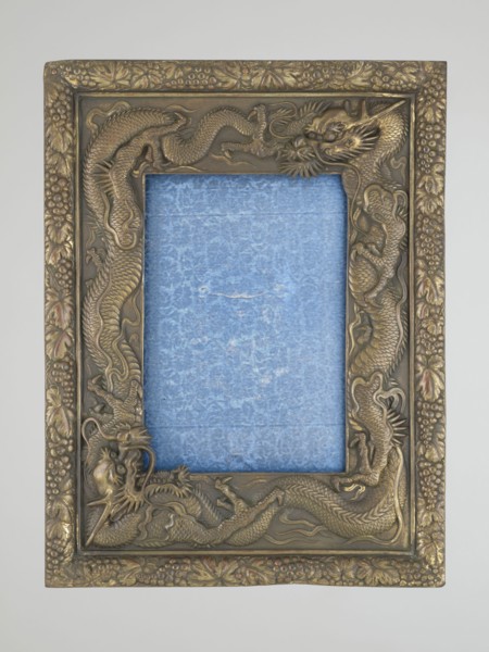 Frame with glass and raised back support covered with blue silk with floral patterns; originally