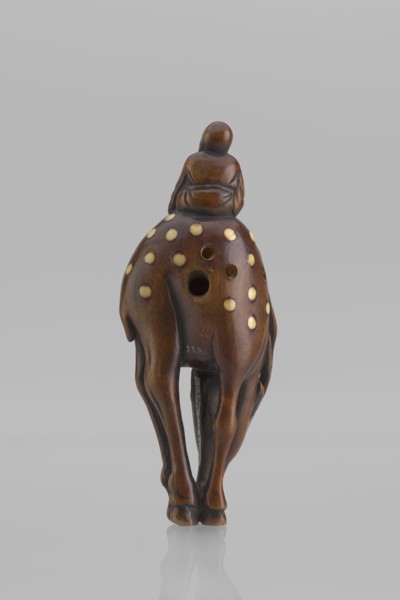 Netsuke in the shape of Fukurokuju riding a deer. The deer has all its legs put together so that