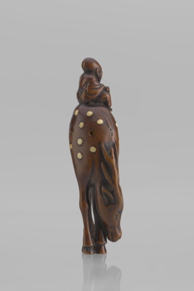 Netsuke in the shape of Fukurokuju riding a deer. The deer has all its legs put together so that