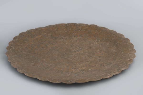 Plate, flat without a distinct rim. Decorated with a dense arabesque in the hataji style and an