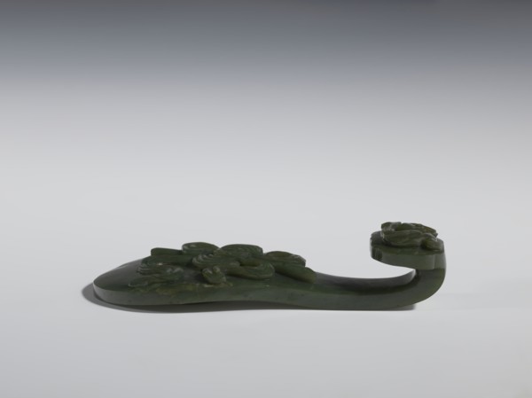 Belt clasp. Scepter head with a bas-relief stylized lizard; shaft with a Taoist emblem of one of