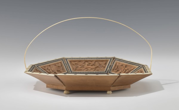 Basket. Octagonal shallow wooden basket with an ivory rim and handle. Inside the basket is a relief