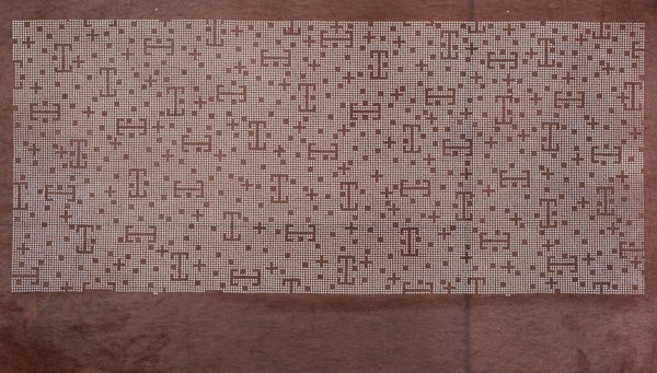 A katagami dyeing stencil cut into a pattern composed of small crosses, squares, and lines against