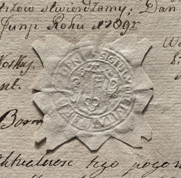 Round imprint of the seal of the town of Stopnica. In a decorative cartouche a key - tooth up.