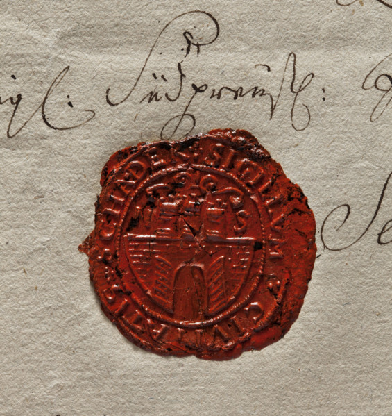Oval wax impression of the seal of Szadek. Town wall with an open gate, on it three towers with