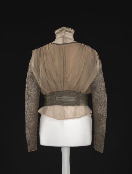 Blouse. Made of beige-gold muslin, short, bloused, fitted at the waist with a belt draped in three