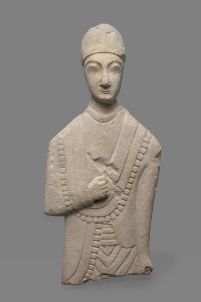 Fragment of a votive figure of a man. The fragment depicts a standing man dressed in a tutulus and