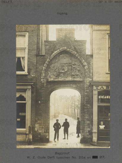 Entrance gate to the Bagijnhof in Delft with three people, Bagijnhof. WZ Oude Delft between No.