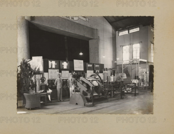Men posing in the factory by a display of machines, album page, photograph, Album page with a photo