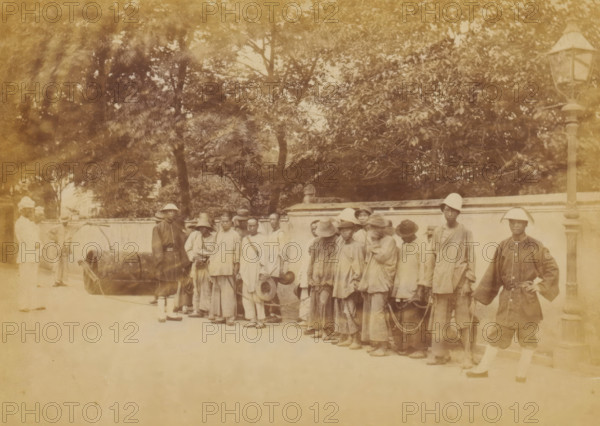 Group of Chinese people chained together under the supervision of guards, The chain-gang,