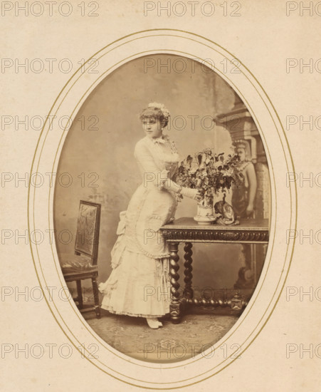 Portrait of a woman standing by a table with flowers, album page, photograph, cabinet photograph,