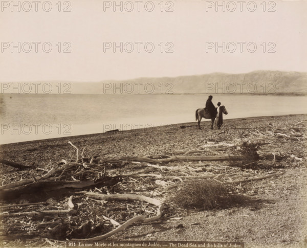 Rider and man on the shore of the Dead Sea with washed-up branches in the foreground, La mer Morte