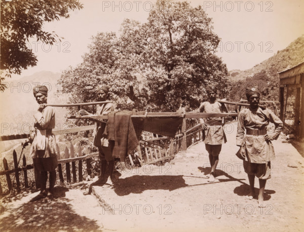 Four Indian men in unform life a palanquin, India, photograph, signature: 'SH Dagg', inscription: