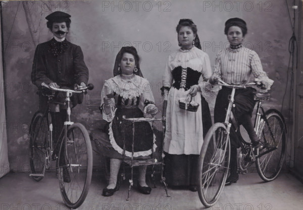 Group portrait of four unknown girls in traditional costume with bicycles, photograph, inscription: