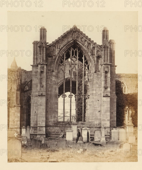 View of a window of the ruins of Melrose Abbey with two men in front of it, photograph, page,