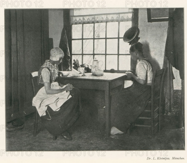 Two women sitting at a table doing needlework, page, photomechanical print, photographer: LL