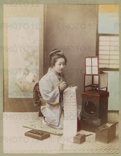 Woman writes a letter in an interior, photograph, page, photographer: attributed to Kusakabe
