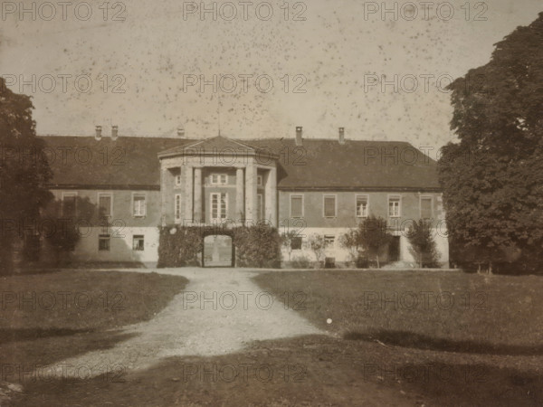 Front view of a country house with a gazebo-shaped central section, with trees on either side and a