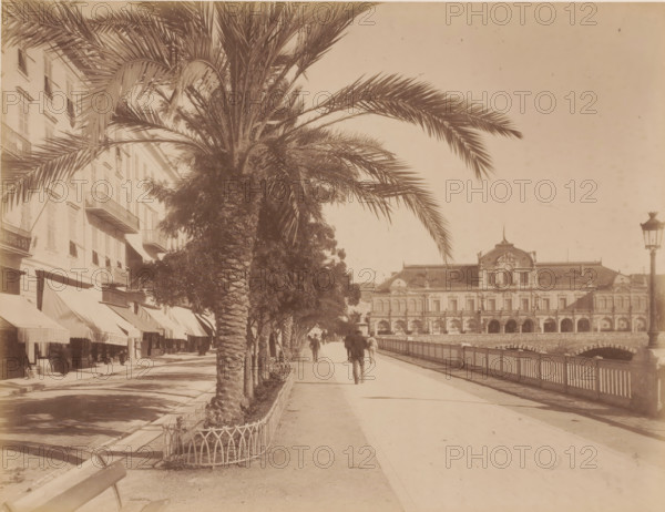 Boulevard, France ?, photograph, View of the boulevard with shops on the left, a bridge and behind
