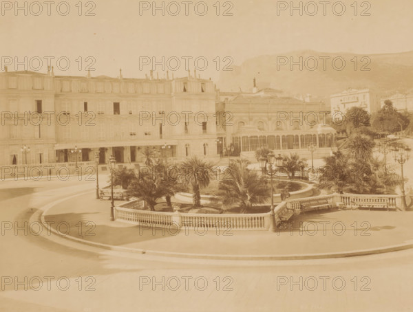 Square with roundabout with palm trees and pond in the middle and houses around it, photograph,
