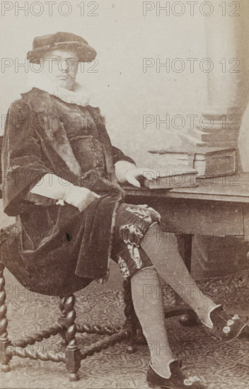Portrait of a man in a suit sitting at a table, identified as N. Dirkzwager, album page,