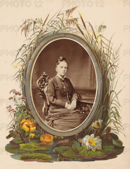 Portrait of a woman sitting on a chair at a table on which an album lies, photograph, cabinet