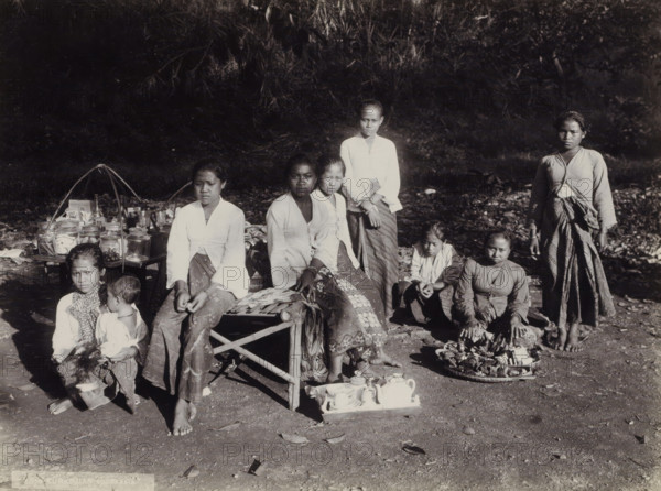 Women and children with goods displayed along the side of the road, Indies women and children with