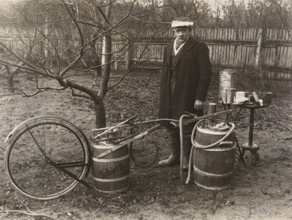 Man by a self-built pesticide spraying system for fruit trees, possibly in Denmark, photograph,