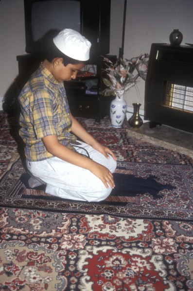 Muslim boy offers a private prayer at his home in LOndon