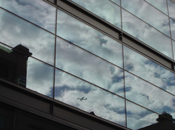 Reflet de nuages et d'un avion dans un immeuble de la City à Londres