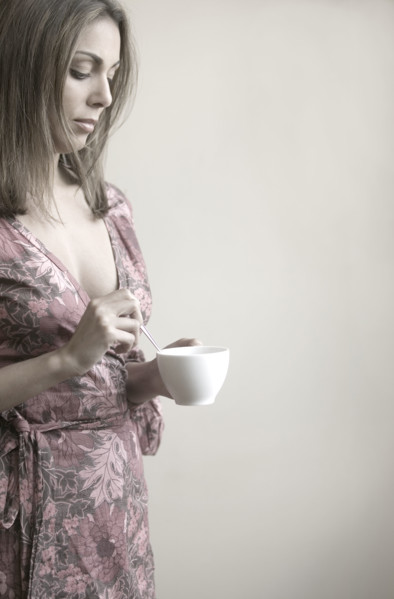 Profile of woman stirring coffee.