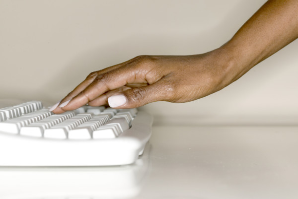 A woman's hand on computer keyboard.