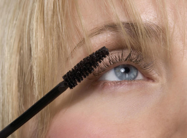 Woman's eye with mascara brush.