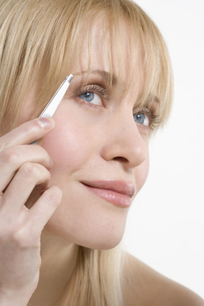 Woman plucking eyebrows.