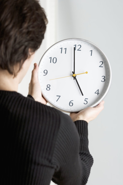 Man from behind holding clock.