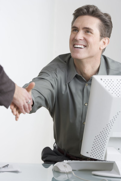 Businessman at desk shaking hands.