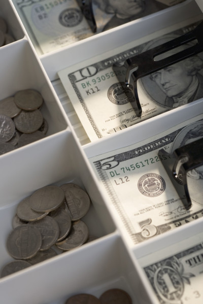 U.S. bills and coins in cash register.
