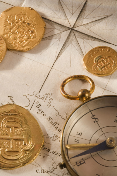 Still life of pieces of gold map and compass.