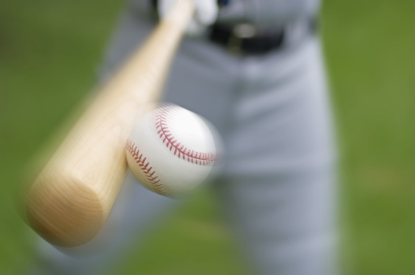 Closeup of baseball player hitting ball.
