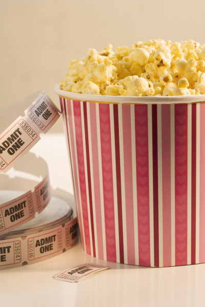 Still life of popcorn and ticket to a movie.