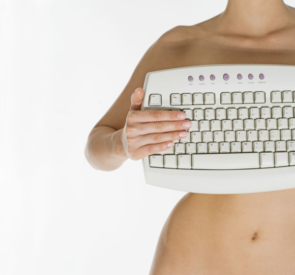 Nude female holding computer keyboard.
