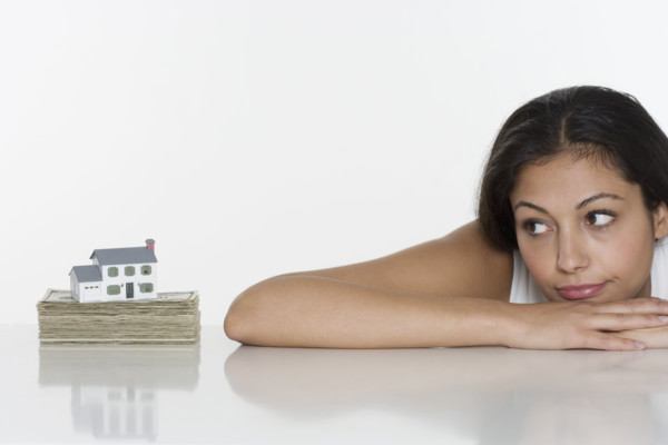 Woman looking at miniature house and money.