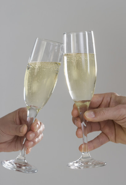 Profile of hands toasting champagne flutes.