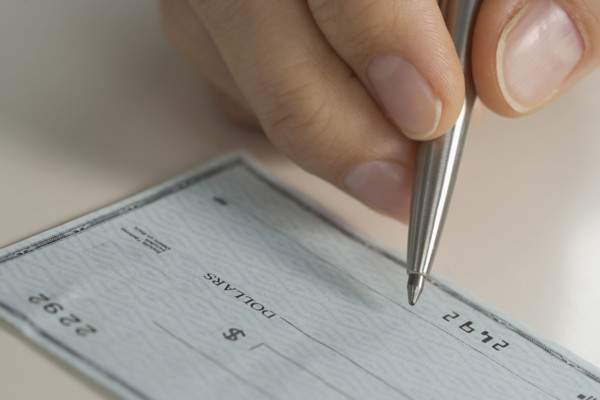 Closeup of hand writing check.