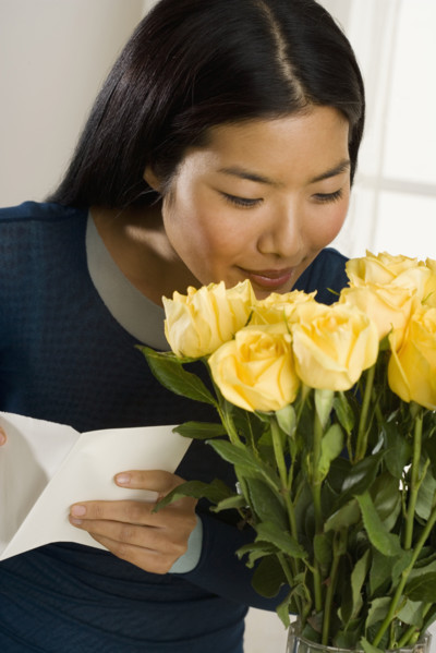 Woman smelling bouquet of roses.